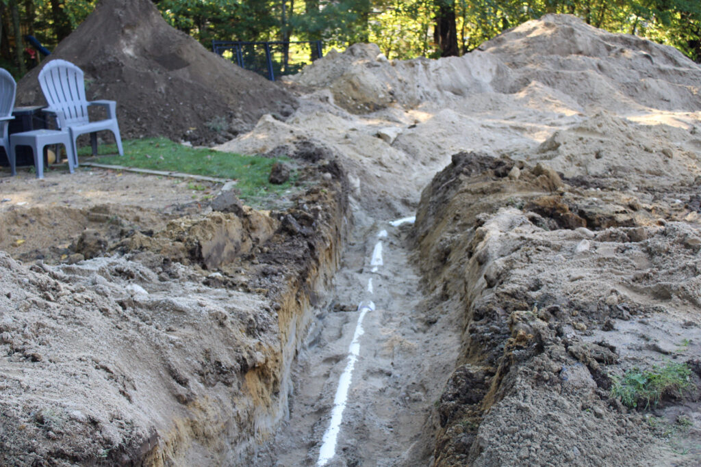 new septic system piping leading between tank and leach field waiting for final inspection prior to final grade